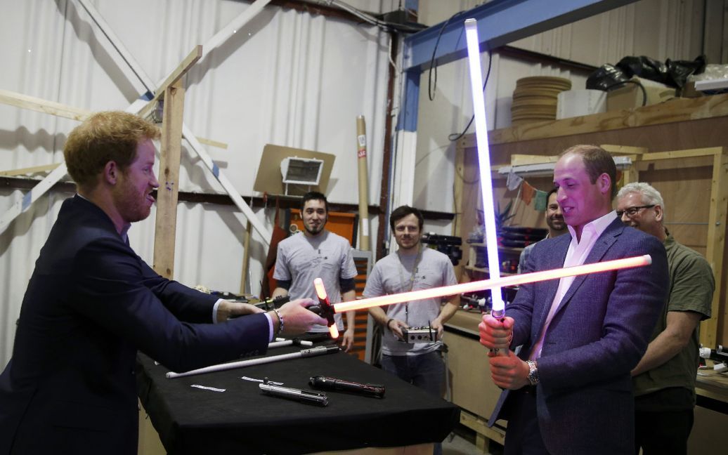 Британский принц Уильям пытается попасть световым мечом в своего брата принца Гарри во время визита в студию Pinewood, где проходили съемки "Звездных войн". / © Reuters