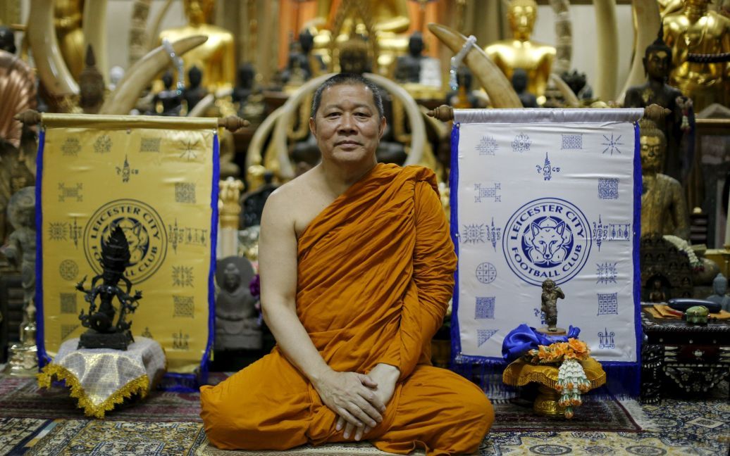 Буддійський монах позує для фото поруч зі святими полотнами з логотипом англійського футбольного клубу &ldquo;Лестер Сіті&rdquo;. Монах благословив команду у своєму храмі в Бангкоку, Таїланд. / © Reuters