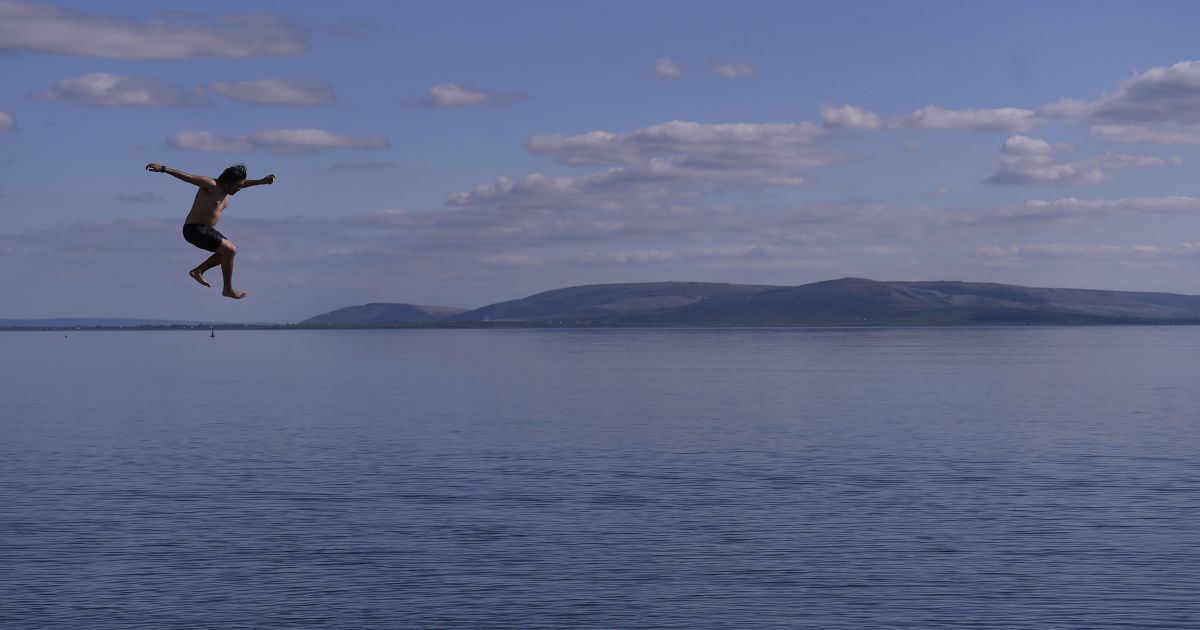Молодой человек прыгает в воду на пляже Солтхилл в Голуэй, Ирландия. / © Reuters