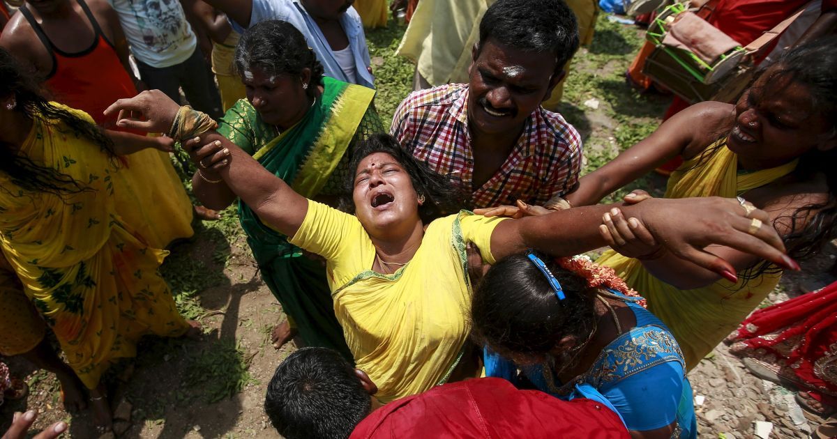 Женщина впадает в транс во время религиозной процессии, посвященной богине Мариамман, в Мумбаи, Индия. / © Reuters