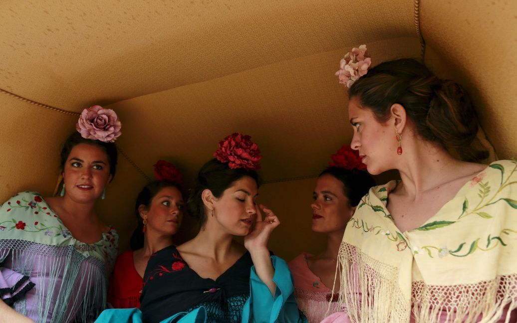 Жінки у сукнях фламенко сидять на візку, перш ніж взяти участь у виставці перед боєм биків у столиці Андалусії Севільї, на півдні Іспанії. / © Reuters