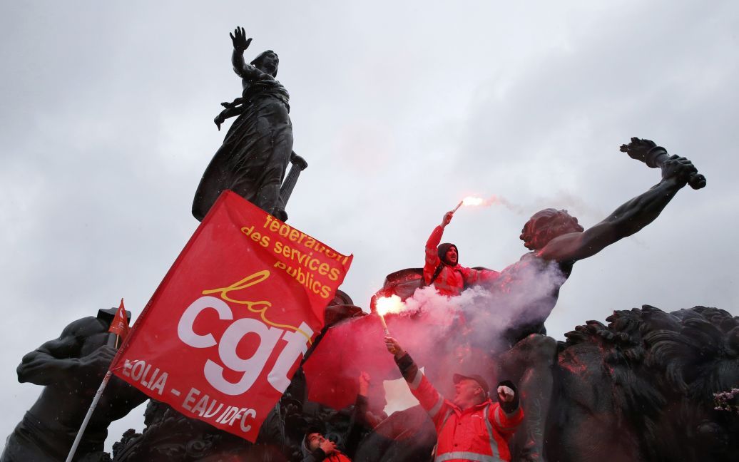 Активісти робітничих профспілок тримають факели безпеки, стоячи  на статуї на Площі нації у Парижі під час демонстрації проти змін трудового законодавства у Франції. / © Reuters
