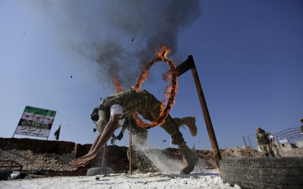 Бойовик сирійської опозиції стрибає через петлю вогню, демонструючи свою майстерність під час військового вишколу в таборі на півночі провінції Хама, Сирія. / © Reuters