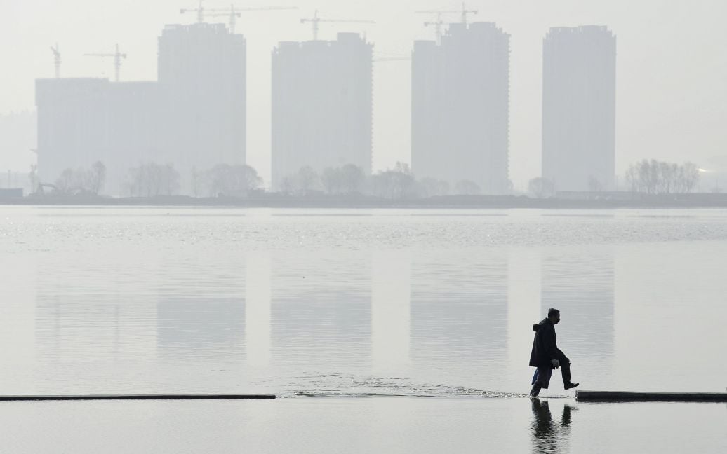 Человек идет в искусственном озере вблизи жилых домов в городе Тайюань, провинция Шаньси, Китай. / © Reuters