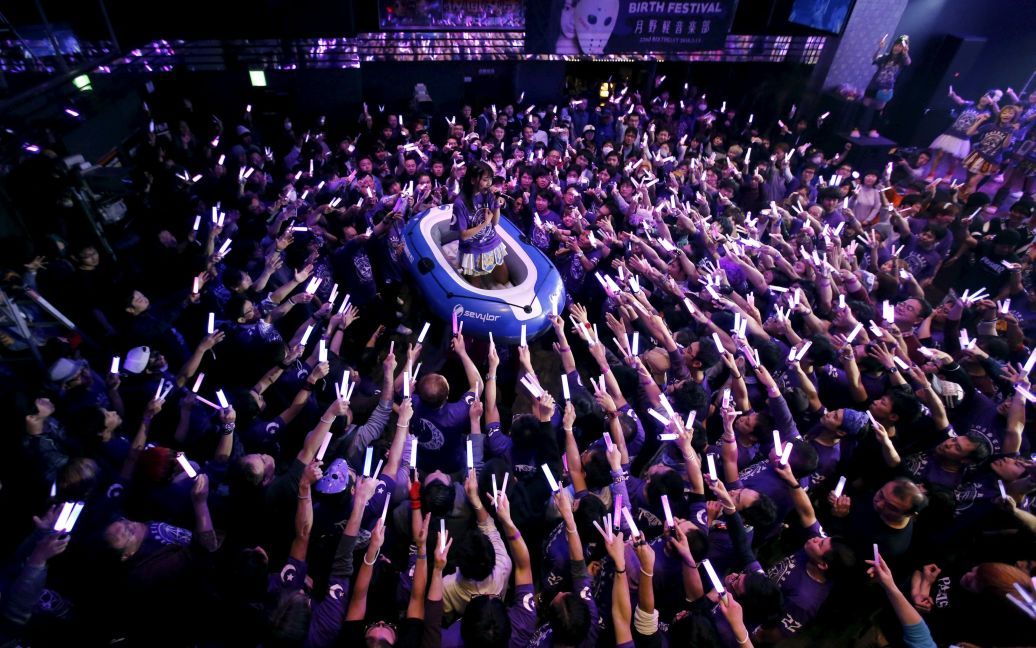 Моа Цукино, член японской идол-группы Камни Джоши (Замаскированные девушки), поет на лодке посреди толпы поклонников во время концерта в Токио. / © Reuters