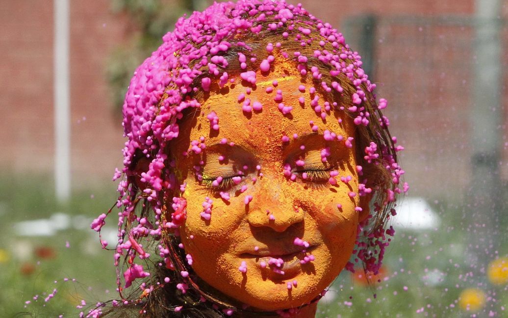Студентка із змащеним кольоровим порошком обличчям святкує Холі в університетському містечку в місті Чандігарх, Індія. / © Reuters