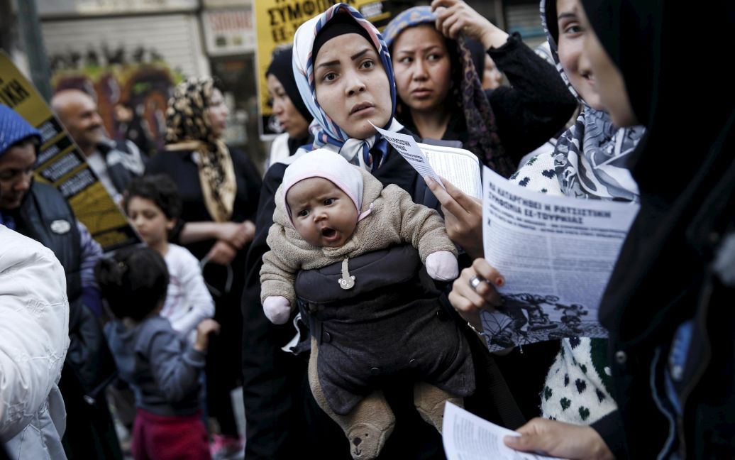 Афганська мігрантка несе свою дитину поряд з активістами і студентами, які беруть участь в акції протесту проти недавнього закриття кордону через Балкани, в Афінах, Греція. / © Reuters