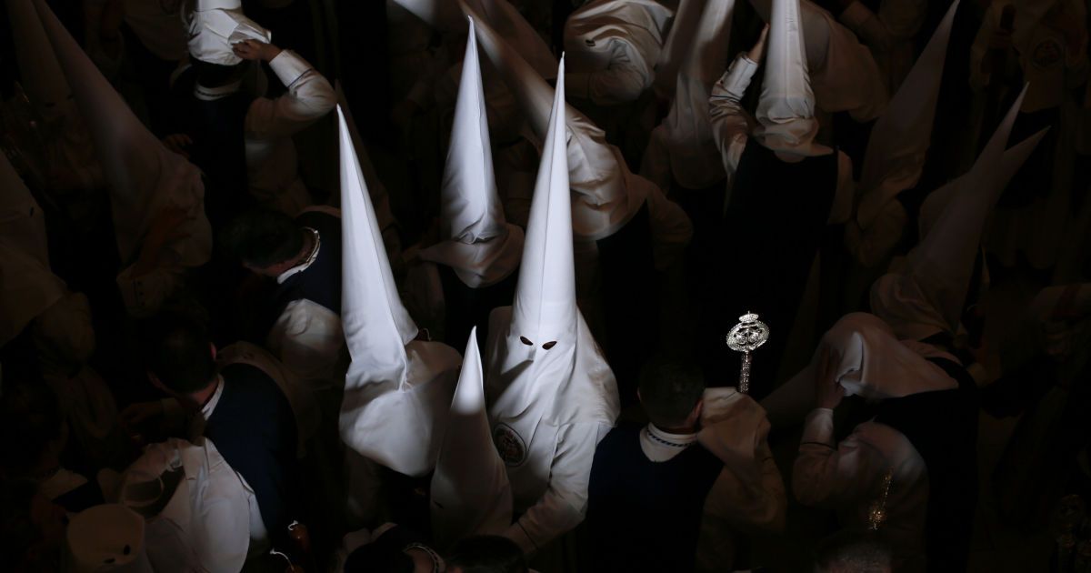 Члены братства Лос Негритос ждут шествия в честь Страстной недели в столице Андалусии Севилье, на юге Испании. / © Reuters