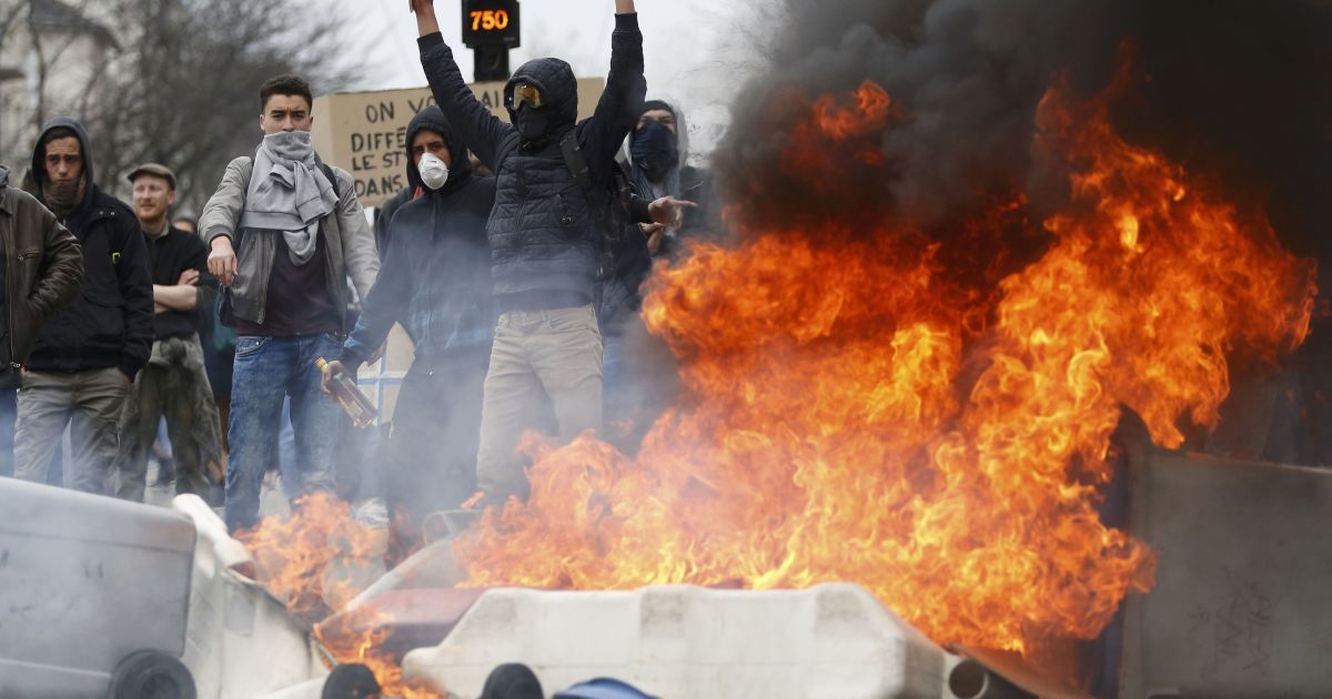 Демонстранты стоят вблизи горящего мусора во время акции протеста французских студентов средних школ и университетов против законопроекта о реформе труда во Франции. / © Reuters