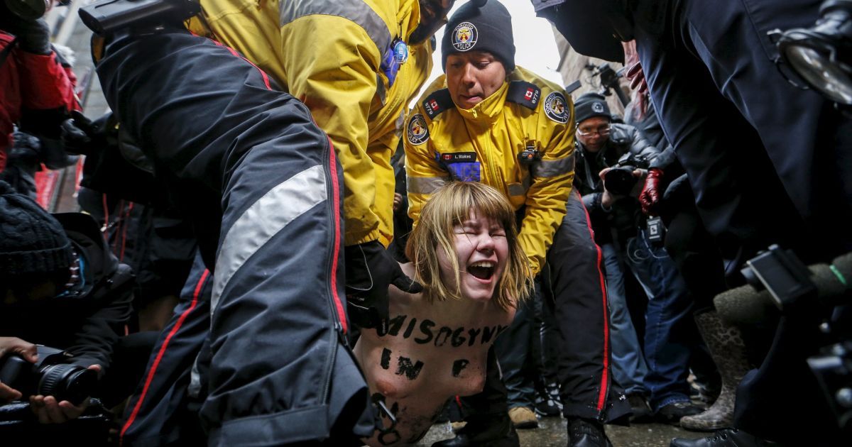Обнаженная топлес протестующая задерживается полицией во время акции протеста против решения судьи Онтарио, который признал бывшего владельца канадского радио Цзянь Гомеша невиновным по четырем обвинениям в сексуальном насилии. / © Reuters