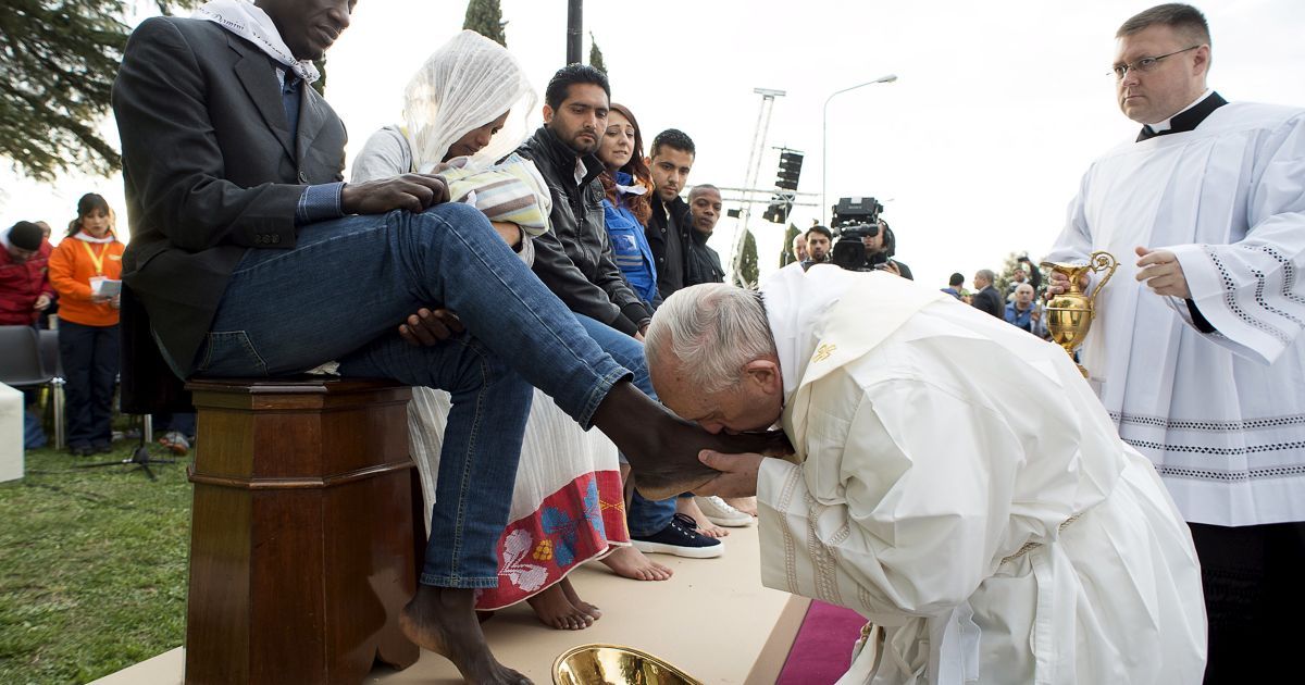 Папа Римский Франциск целует ногу мигранту во время ритуала омовения ног в центре беженцев недалеко от Рима, Италия.