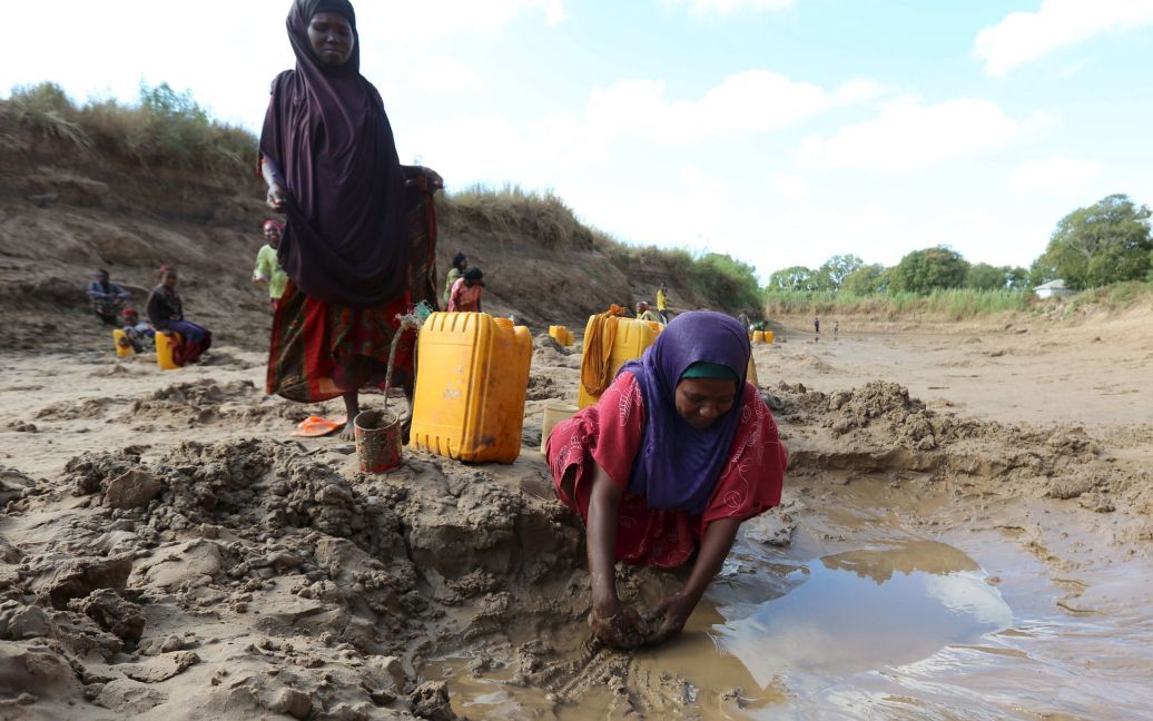 Жінки набирають воду з неглибоких свердловин, виритих уздовж русла річки Шабелле, яка засихає через посуху у Сомалі. / © Reuters