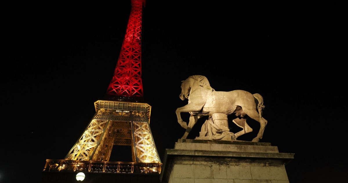 Эйфелева башня в Париже светится цветами бельгийского флага.