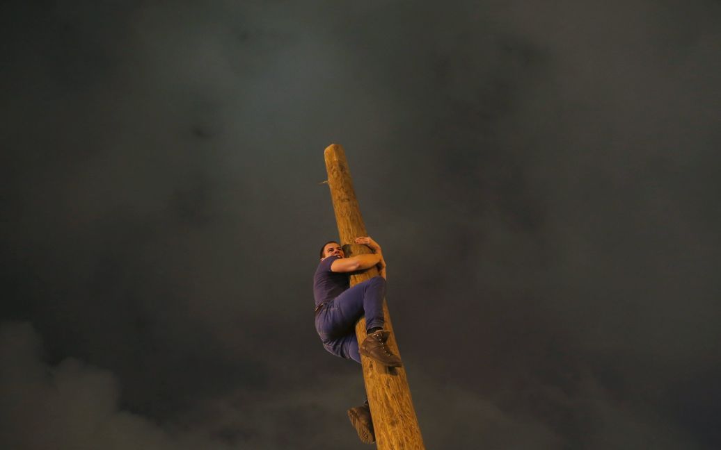 Человек поднимается вверх по деревянному столбу во время празднования Масленицы в парке Горького в Москве, Россия. / © Reuters