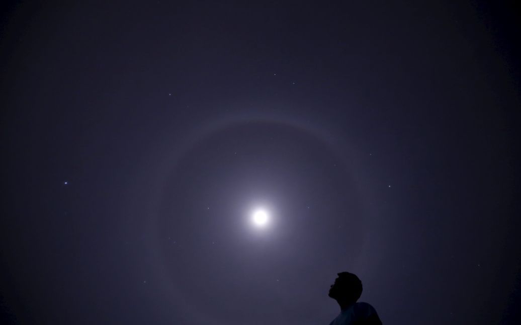 Человек смотрит в сторону лунного гало в небе над Катманду, Непал. / © Reuters