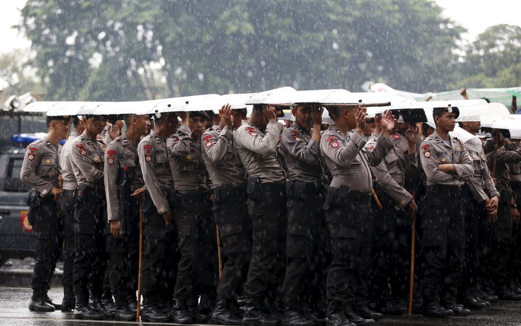 Полиция использует щиты, чтобы укрыться от дождя во время акции протеста со стороны водителей такси за пределами президентского дворца в Джакарте, Индонезия. / © Reuters
