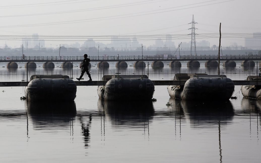 Поліцейський йде по понтонному мосту, прокладеному в водах річки Ямуна, щоб дістатися до місця проведення Всесвітнього фестивалю культури на березі річки в Нью-Делі, Індія. / © Reuters