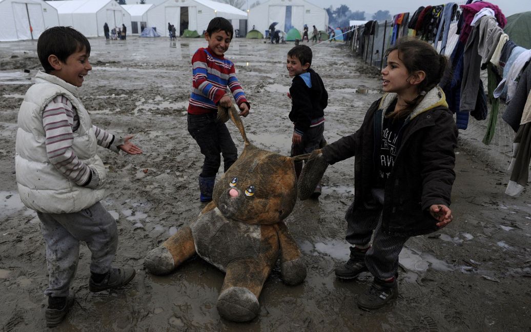 Дети-беженцы играют с мягкой игрушкой в ​​палаточном лагере на греко-македонской границе, недалеко от села Идоменей, Греция. / © Reuters