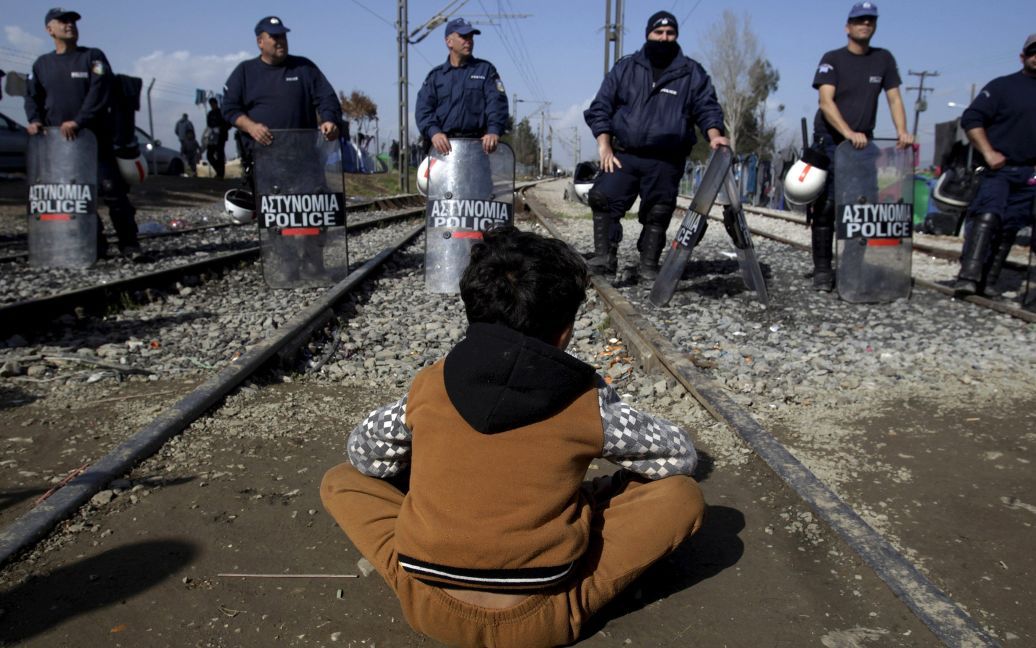Беженец сидит перед греческими спецназовцами во время акции протеста на греко-македонской границе, недалеко от села Идоменей. / © Reuters