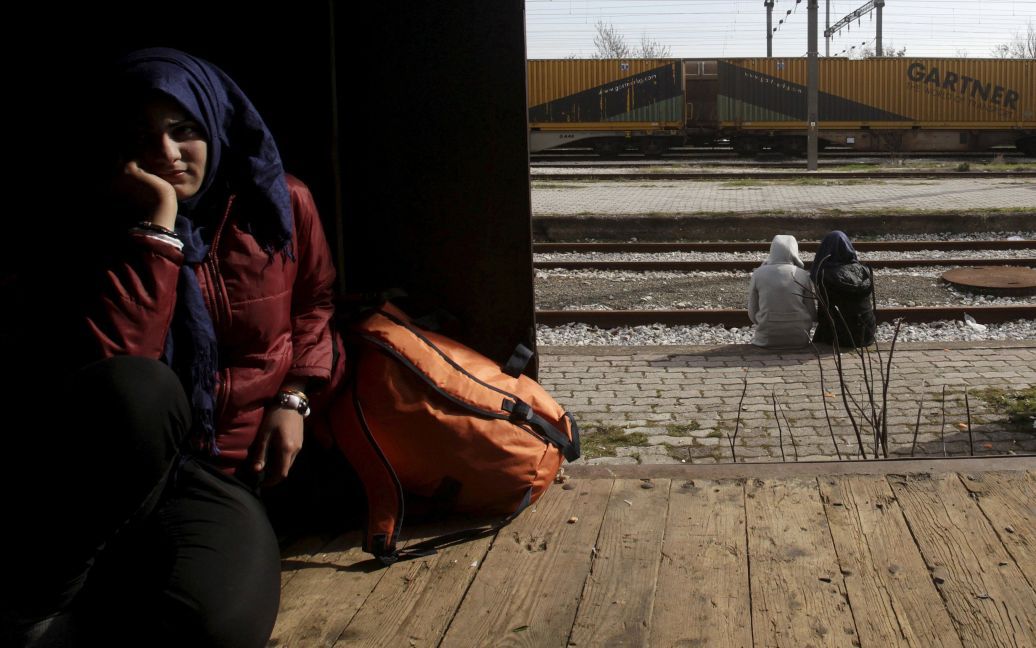 Мігрантка знаходить притулок у вагоні у той час, як інші сидять біля залізничних колій, нав греко-македонському кордоні, недалеко від села Ідоменей, Греція. / © Reuters