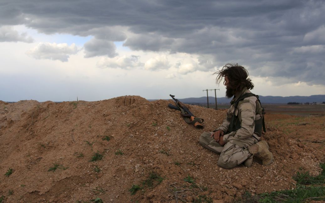 Боевик сирийской оппозиции сидит на точке наблюдения с оружием в деревне Аль-Латамна в Сирии. / © Reuters