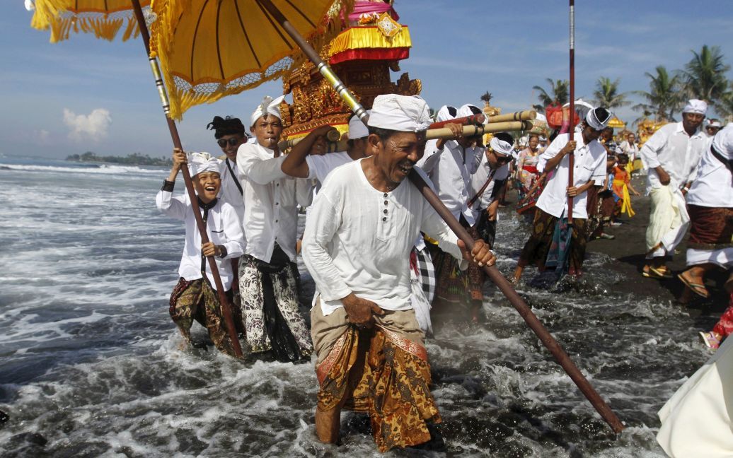 Балийские индуисты несут Пратимас или символы Бога, на пляже во время церемонии очищения перед праздничным днем ​​Ниепи. В этот день местные индуисты отмечают балийский новый год, они сохраняют тишину, не могут использовать свет, фейерверки, им запрезено работать, путешествовать и развлекаться. / © Reuters