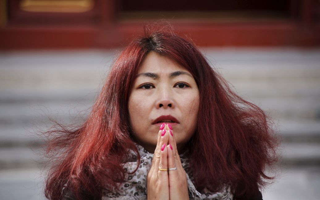 Чен Липин молится в Храме Ламы в Пекине за своего мужа Ю Куна, который был на борту рейса МН370 Малайзийских Авиалиний, пропавшего без вести в 2014 году. / © Reuters