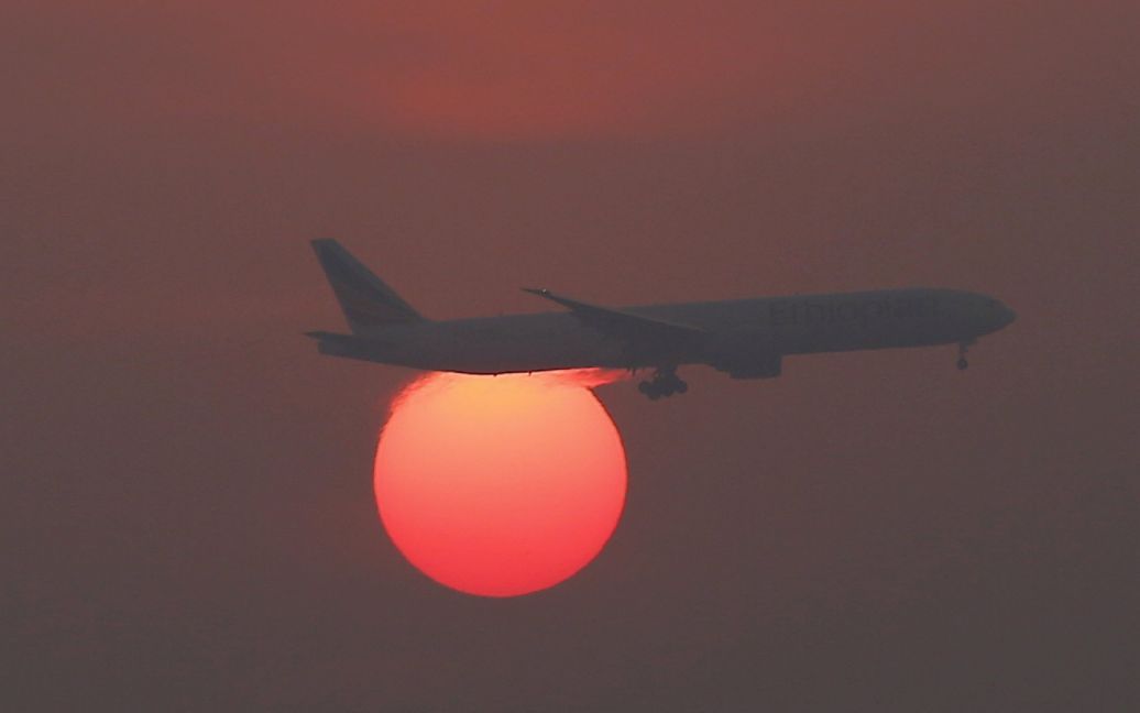 Самолет летит над заходящим солнцем в небе в международном аэропорту Пекина, Китай. / © Reuters