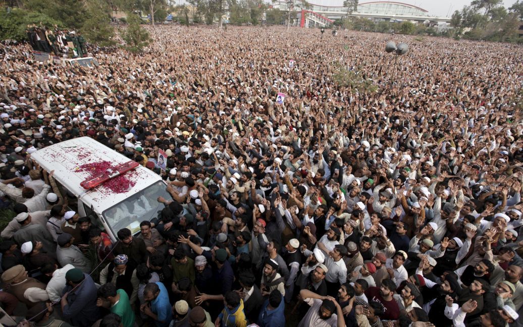 Люди идут рядом с машиной скорой помощи, перевозящий тело казненного полицейского Мумтаза Кадри во время его похорон в Пакистане. Кадри был казнен за убийство губернатора одной из провинций, который призывал смягчить пакистанские законы о суровом наказании за кощунство. / © Reuters