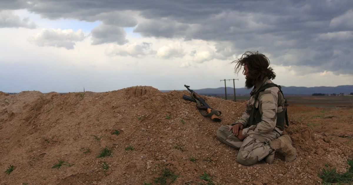 Боевик сирийской оппозиции сидит на точке наблюдения с оружием в деревне Аль-Латамна в Сирии. / © Reuters