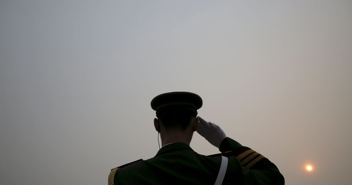 Солнце видно сквозь смог в сильно загрязненный день в то время, как полицейский салютует делегатам, которые прибывают в Большой зал народов накануне субботней церемонии открытия Национального народного конгресса в Пекине, Китай. / © Reuters