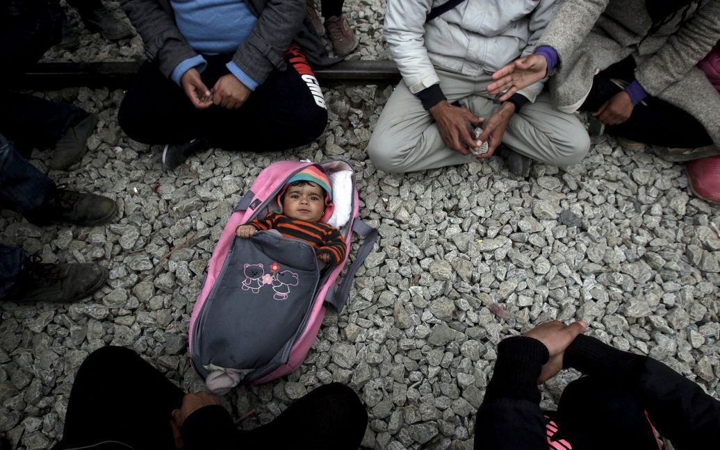 Ребенок лежит на земле среди беженцев и мигрантов, ожидающих пересечения греко-македонской границы недалеко от греческого села Идоменей. / © Reuters
