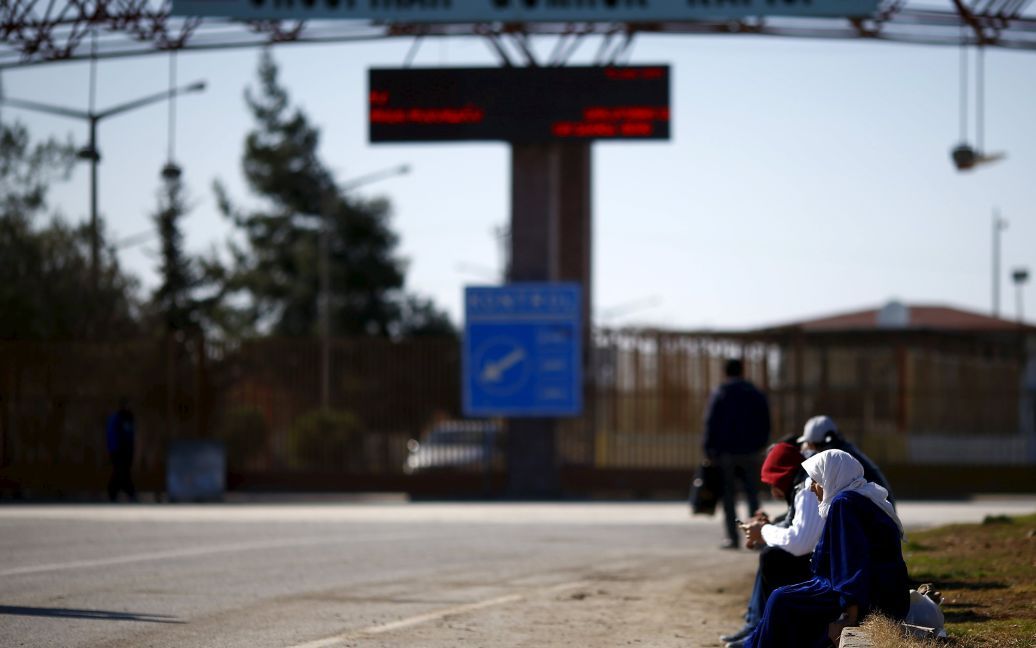Люди сидять на тротуарі, на перетині кордону з Туреччиною, у південно-східному місті Кіліс. / © Reuters