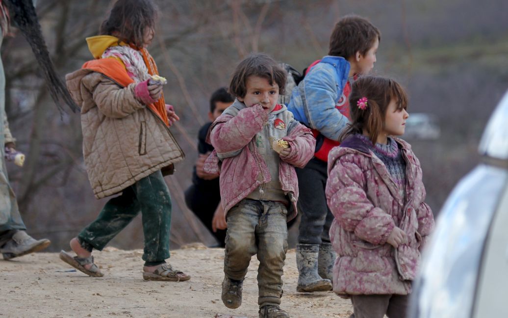 Дети-беженцы, все в грязи, ждут разрешения пересечь границу в Турцию со своими семьями в городе Хирбет Аль-Джоз. / © Reuters
