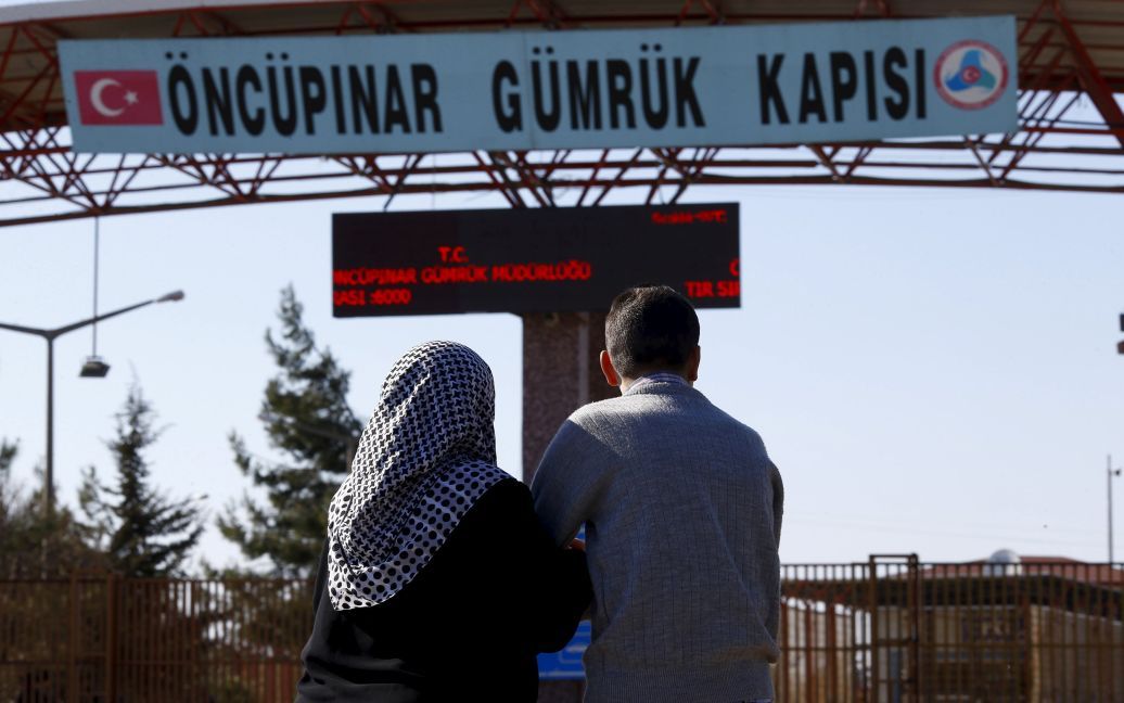 Двое сирийцев ждут на турецкой стороне границы своих родителей, которые должны прибыть из Сирии, в юго-восточном городе Килис. / © Reuters