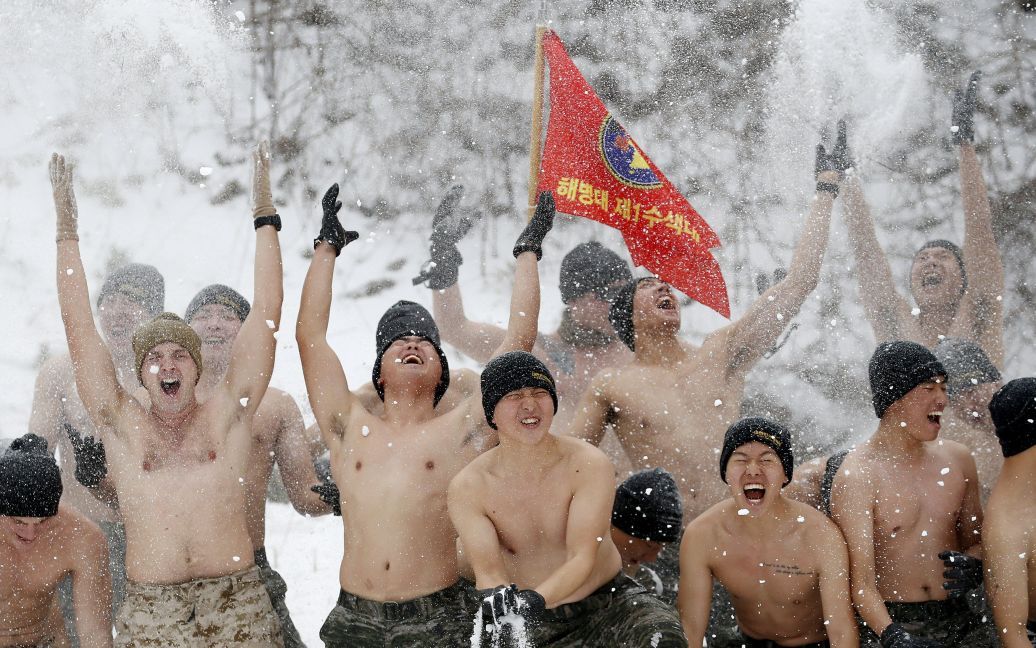 Полуобнаженные южнокорейские и американские морские пехотинцы бросают снег во время зимних учений в Пхенчхане, Южная Корея. / © Reuters