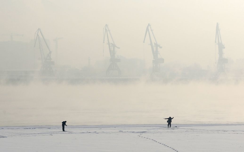 Чоловіки вудять рибу на покритій льодом затоці річки Єнісей у сибірському місті Красноярську. Температура повітря складає мінус 24 градуси за Цельсієм. / © Reuters