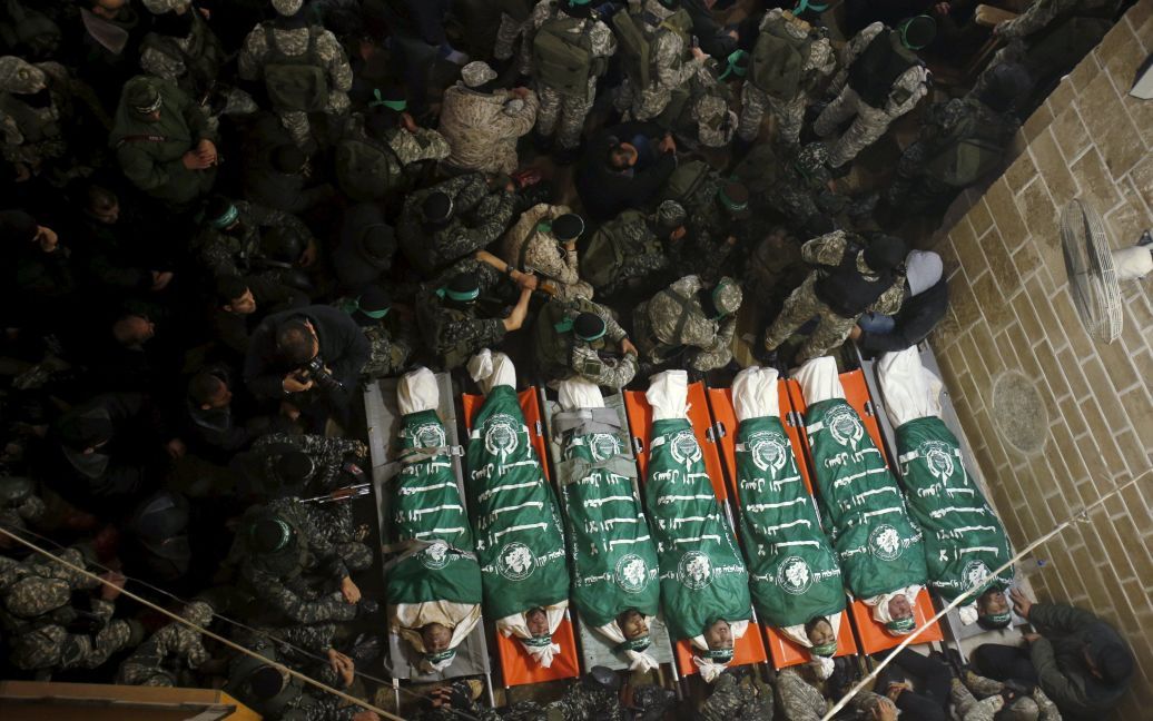 Палестинские боевики ХАМАСа сидят рядом с телами своих товарищей, погибших при обрушении тоннеля на восточной границе сектора Газа с Израилем. Семеро боевиков погибли, пытаясь с помощью тоннеля атаковать израильских военных. / © Reuters