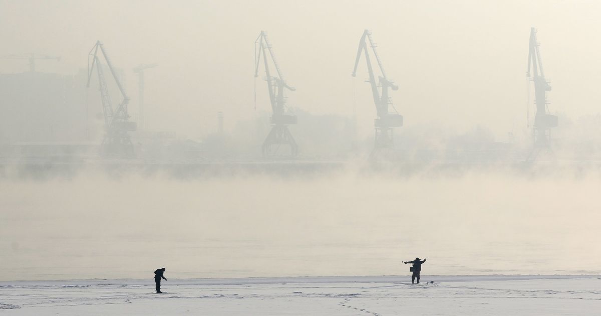 Мужчины удят рыбу на покрытом льдом заливе реки Енисей в сибирском городе Красноярске. Температура воздуха составляет минус 24 градуса по Цельсию. / © Reuters