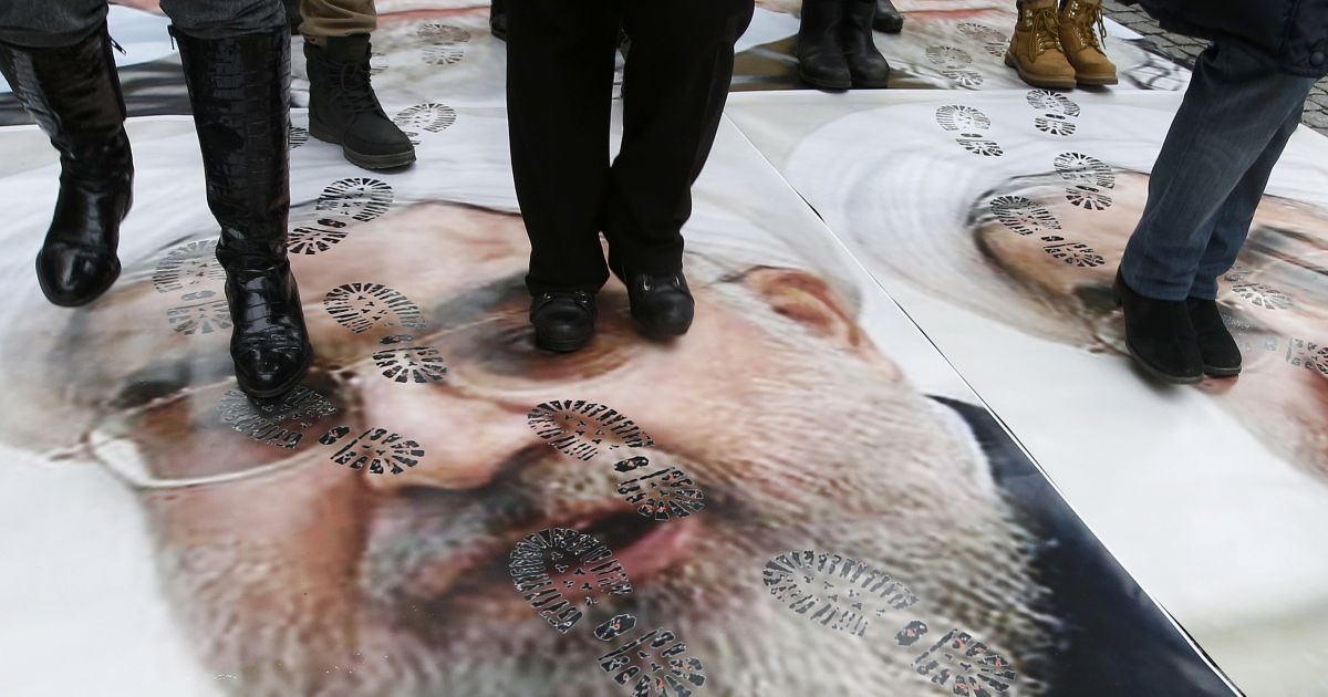 Люди ходят по портретам президента Ирана Хассана Роухани во время акции протеста против его визита во Францию ​​в центре Парижа. Роухани отправился с официальными визитами в Италию и Францию ​​- это стало первым визитом президента Ирана в Европу за 16 лет. / © Reuters