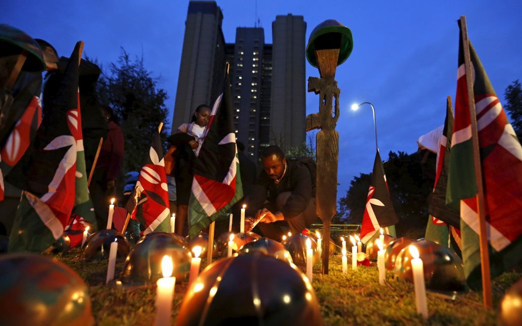 Человек зажигает свечу у муляжа автомата и шлема, размещенных на земле, символизирующие кенийских солдат, служивших в Миссии Африканского союза в Сомали. На прошлой неделе более 100 кенийских военных были убиты во время нападения боевиков "Аль-Шабааб" на базу недалеко от границы с Кенией. / © Reuters