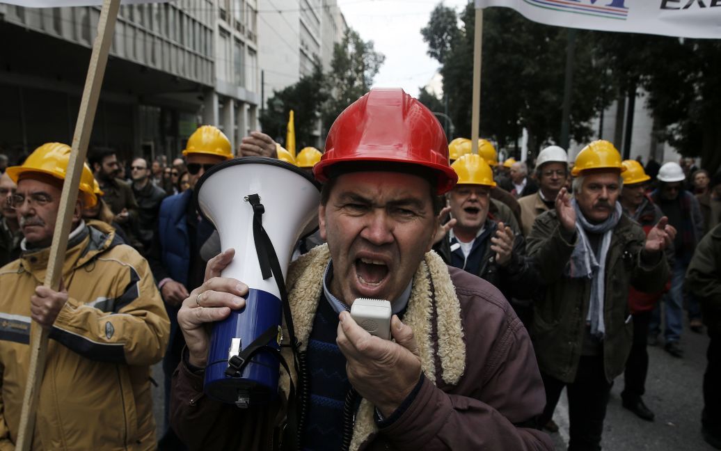 Греческие инженеры в защитных шлемах выкрикивают лозунги во время демонстрации против запланированных пенсионных реформ в Греции. / © Reuters