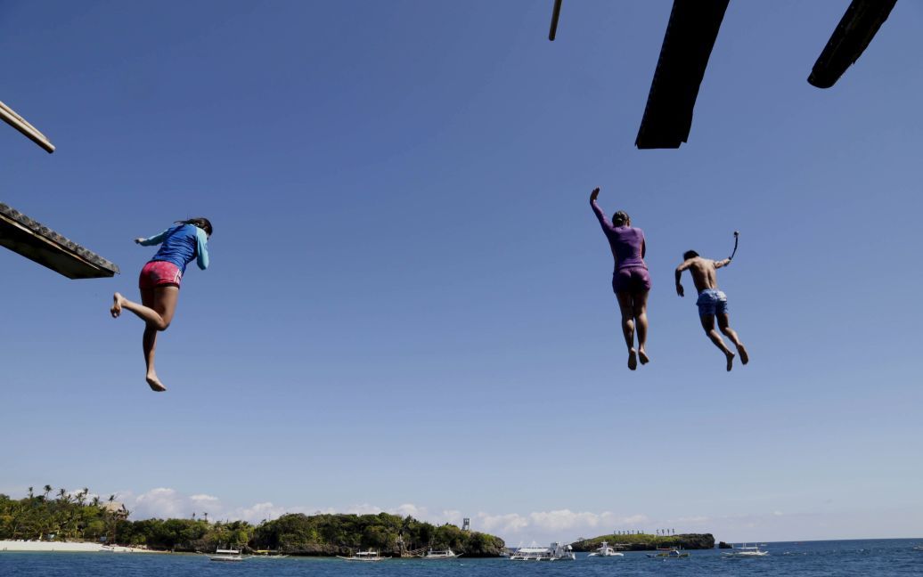Туристи стрибають з 6-метрової скелі на одному з острівців біля острова Боракай, Філіппіни. / © Reuters