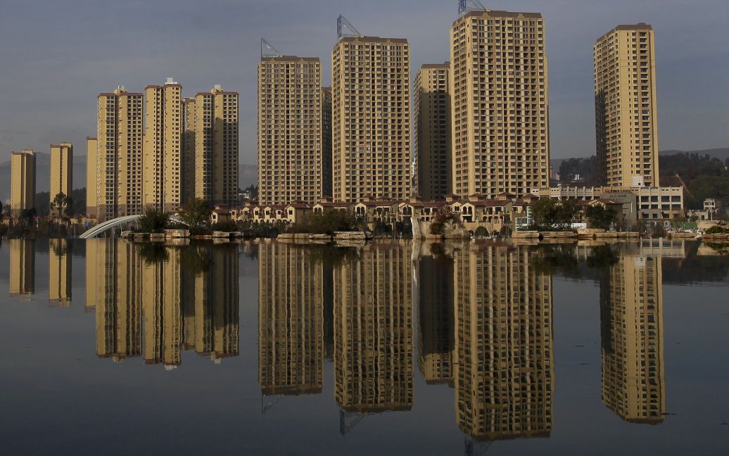 Новые жилые здания отражаются в искусственном озере в провинции Юньнань, Китай. / © Reuters