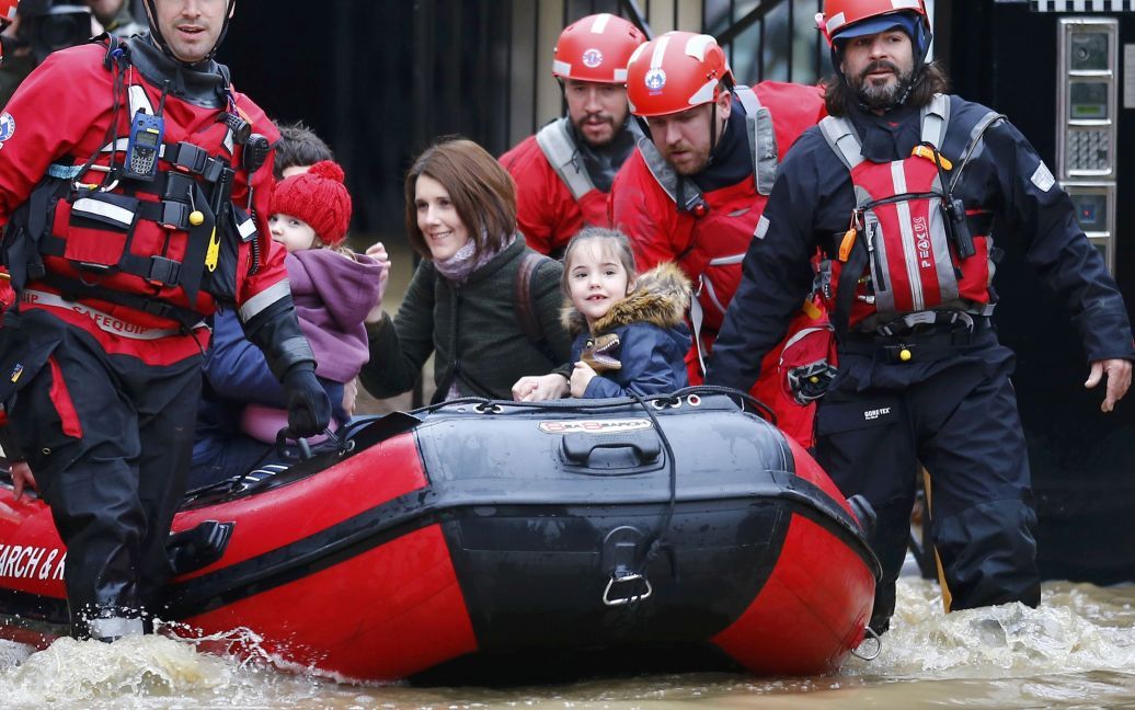 Врятована від затоплення сім&rsquo;я за допомогою рятувальної команди покидає центр міста Йорк, Англія. Великобританію накрили потужні повені, які змусили покинути свої будинки тисячі людей. / © Reuters