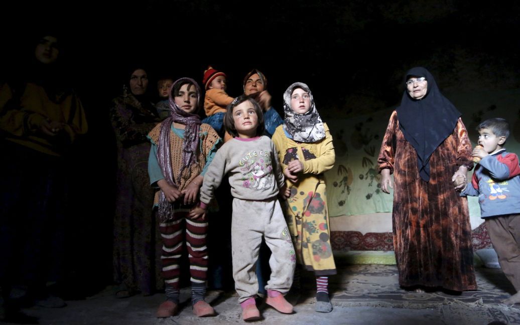 Женщины и дети стоят внутри импровизированного бомбоубежища в подземной пещере в Ом-эль-Сир на юге провинции Идлиб, пытаясь пережить авиаудар. / © Reuters