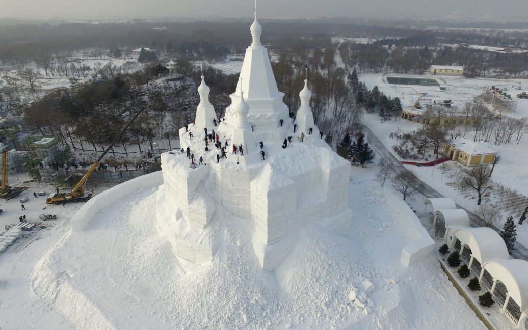 Работники строят ледяной дворец накануне ежегодного Международного фестиваля льда и снега в Харбине, Китай. / © Reuters