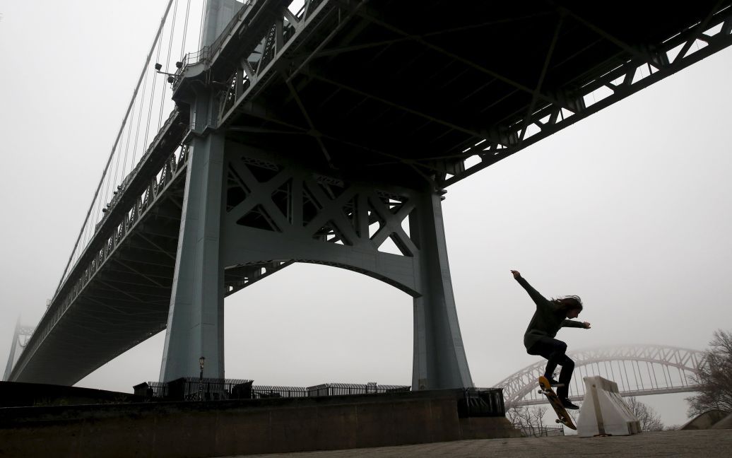 Силует скейтбордиста видно у тумані, який покрив міст Трайборо у Нью-Йорку. / © Reuters