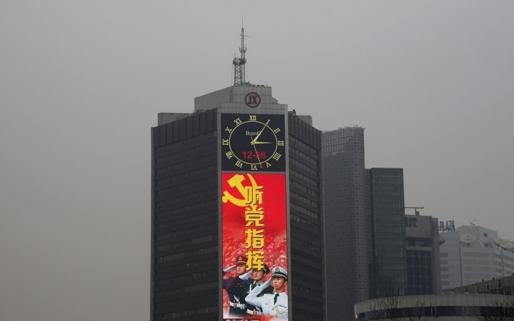 Великий екран на будівлі пропагує китайську Народно-визвольну армію у сильно забруднений смогом день в Пекіні. / © Reuters