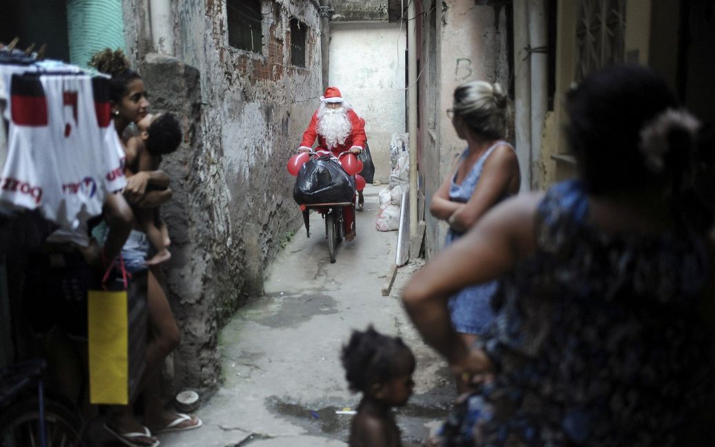 Санта їде на велосипеді серед нетрів, щоб подарувати дітям подарунки в Ріо-де-Жанейро / © Reuters